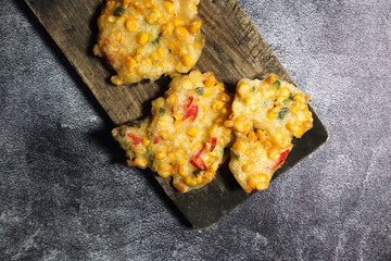 Top view of Bakwan Jagung or Dadar Jagung or Dadar Jagung . Indonesian snack made from corn and flour. Served on a wooden plate. 