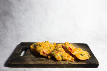 Top view of Bakwan Jagung or Dadar Jagung or Dadar Jagung . Indonesian snack made from corn and flour. Served on a wooden plate. 