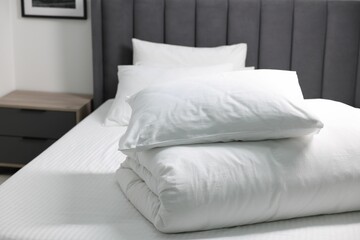 Soft white pillows and duvet on bed at home. Space for text