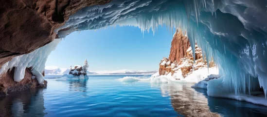 Aluminium Prints Reflection Gazing out from inside the ice cave, the azure sky reflected on the frozen lakes liquid surface, creating an electric blue world in the natural landscape