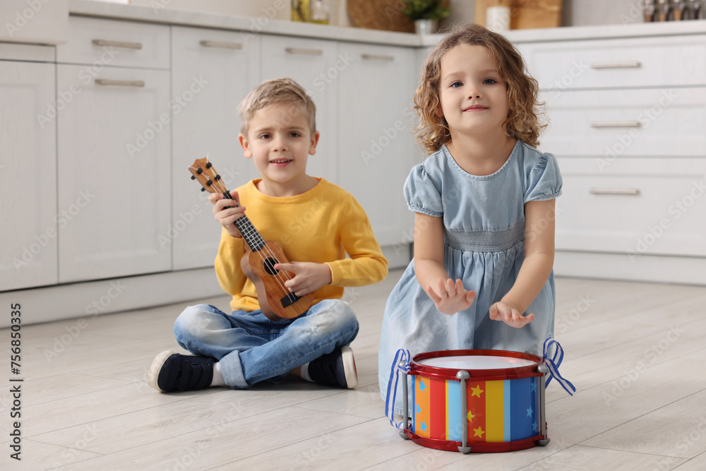 Poster Little children playing toy musical instruments in kitchen