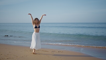 Dancer woman raising hands walking summer beach. Performer moving gracefully