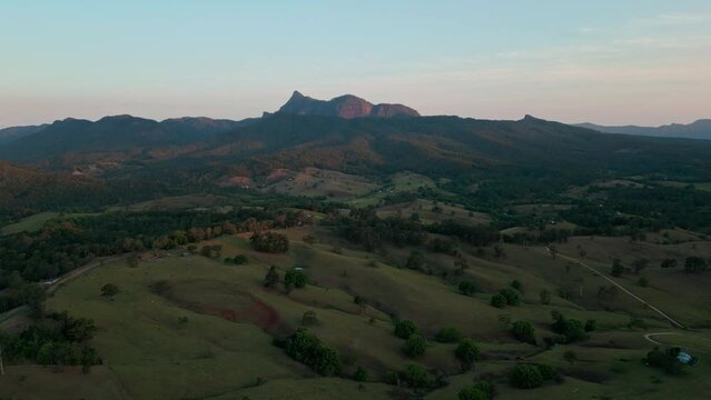 High above the pastures and meadows Mt Warning sits on the horizon with the blue and pink tones of sunset.