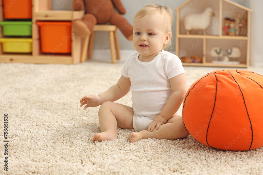 Wall mural children toys. cute little boy and soft toy ball on rug at home, space for text