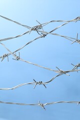 Metal barbed wire on light blue background
