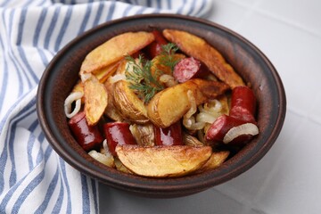 Delicious baked potato with thin dry smoked sausages, onion and dill in bowl on white table, closeup