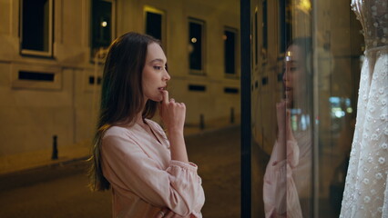 Girl watching bridal dress on mannequin standing store showcase close up. 