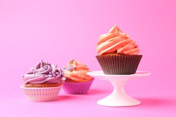 Delicious cupcakes with bright cream and sprinkles on pink background. Space for text