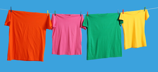 Colorful t-shirts drying on washing line against light blue background, banner design