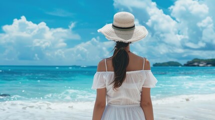 Fototapeta na wymiar Back view young happiness asian traveller woman in white dress and hat standing on beautiful sandy beach. Cute girl enjoy her tropical sea on relax holiday vacation during summer time and sunshine day