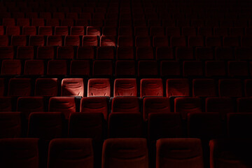 Red empty chairs seats at cinema theater. Low key photo