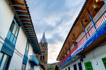 Church tower in the background of a street with colorful balconies in Jardin, Colombia