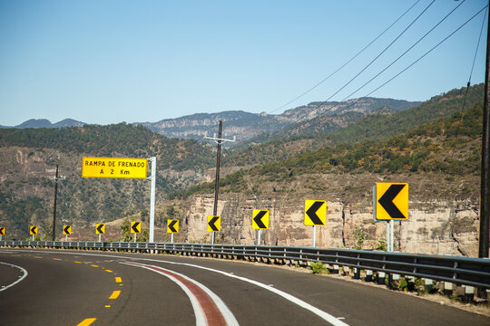 Din&aacute;mica carretera vac&iacute;a vista de alta velocidad desde un auto o una motocicleta. Se&ntilde;ales de transito, flechas y lineas. Curva a la vista. Carretera mexicana.