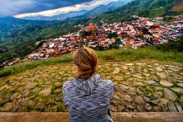 Woman looks at the town of Jerico (Colombia) from a hill at sunset