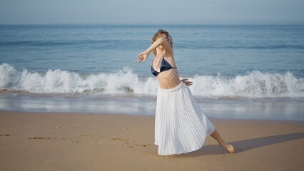 Fototapeta na wymiar Woman making dance performance on picturesque ocean beach. Sensual girl dancer