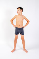 Preteen male fitness model standing shirtless with hands on hips looking to his right