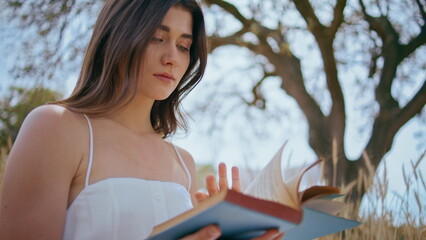 Romantic girl holding book sitting nature closeup. Tranquil woman enjoy reading 