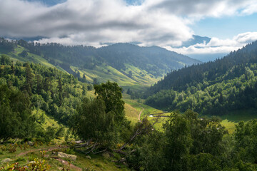 Fototapeta na wymiar The valley of the Malaya Dukka River surrounded by the mountains of the North Caucasus and the tourist trail to the Dukka Lakes on a sunny summer day, Arkhyz, Karachay-Cherkessia, Russia