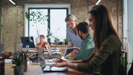 Woman mentor help intern man sitting coworking. Coach explaining work to trainee