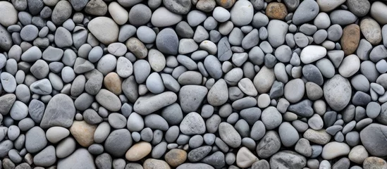  A stack of bedrock rocks creates a unique pattern on the beach resembling a cobblestone road surface, with smaller pebbles and gravel surrounding it © 2rogan