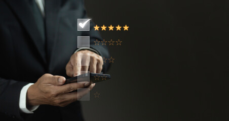 Businessman using mobile phone to give rating showing satisfaction of five-star service on dark background.