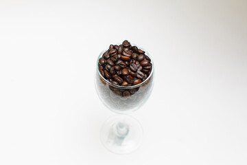 Coffee beans in a glass of wine, top view, close-up, white background.