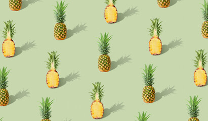 Trendy Colorful  pattern made with of whole and sliced pineapple on pastel green background. Contemporary style. Creative art, minimal aesthetics.Minimal tropical fruit summer concept.