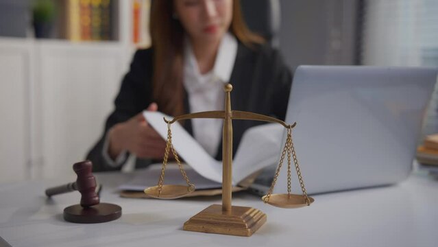 Asian lawyer woman work with hammer and scales of justice in courtroom. 