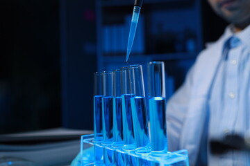 A chemist is testing a newly discovered chemical using a variety of scientific equipment in his lab, The working atmosphere in the laboratory while scientists are doing research.