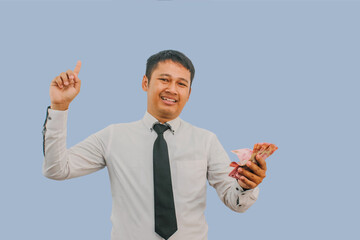 Adult Asian man smiling and pointing finger up while holding indonesian rupiah paper money
