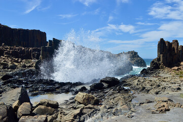 Waves crash into rock formations at Bombo on the South Coast of New South Wales, Australia.