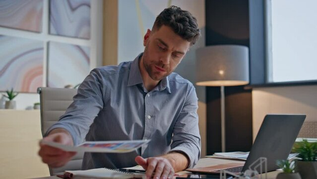 Embarrassed businessman searching documents at messy office workplace closeup