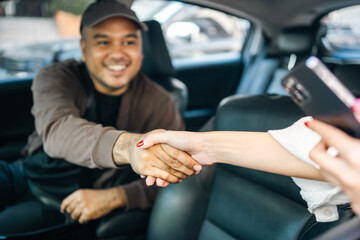 Young asian taxi driver sending and passenger to direction destination. Handshake driver and...