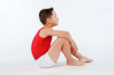 Obraz premium Male youth gymnast sitting on floor waiting for his score after a gymnastics match