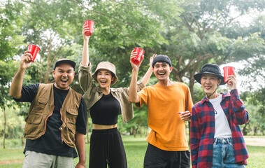 Cheers! Group of asian people friend party camping in nature making toasting with soft drink and beer red cup. Hangout party outdoor in campsite nature forest background on holiday weekend vacation