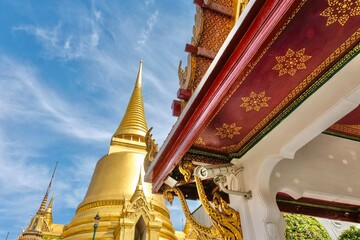 Phra Si Rattana Chedi, a gold bell-shaped stupa, framed by the decorative underside of a pavilion...