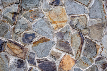 Rough, multi-colored stones in a rock wall at a garden in Taipei