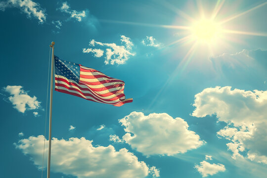 A red, white, and blue American flag is flying in the sky. The sun is shining brightly, casting a warm glow on the flag. Concept of patriotism and pride in the United States
