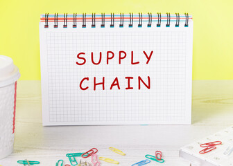 The words Supply Chain written on a checkered notebook on a yellow background