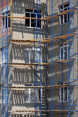 Building under construction with scaffolds. The process of renovating a new building. New construction, exterior wall insulation. construction site