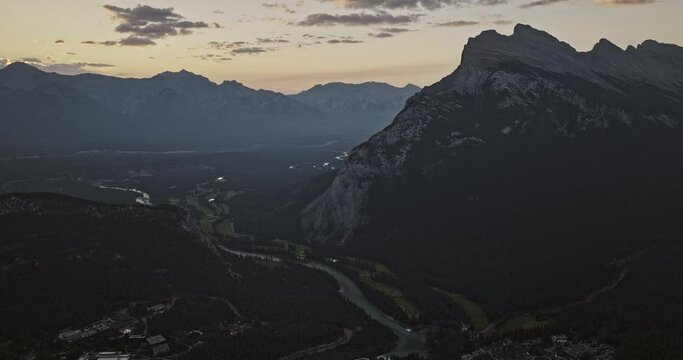 Banff AB Canada Aerial v8 high altitude drone flyover town center capturing forested valley, Bow river course and mountain ranges at sunrise in the summer - Shot with Mavic 3 Pro Cine - July 2023