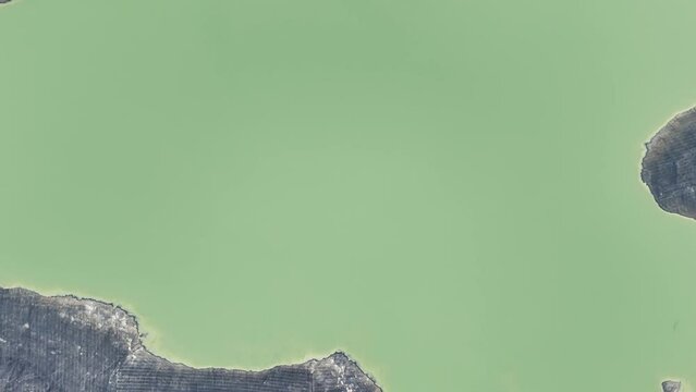 Aerial drone view of a very large dam, artificial lake surrounded by mountains