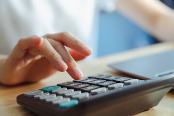 Hand using calculator to calculate income expenses and plans for spending money on home.