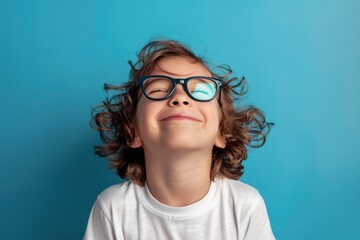 Portrait of a little boy in glasses on a blue background.