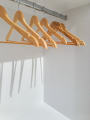 A horizontal detail view of an empty metal coatrack in a white wardrobe with empty wooden coat hangers