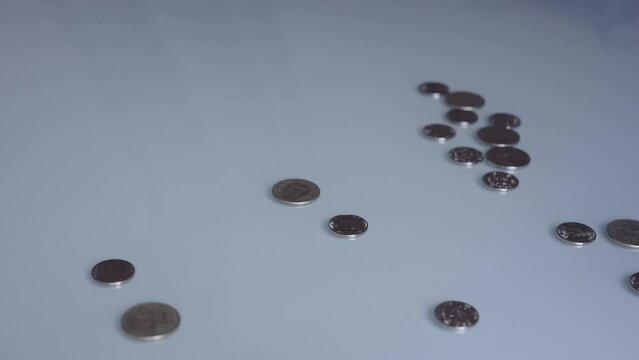 A hand sweeping coins off a table. Take the money from the profits. Business