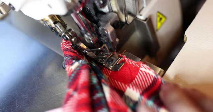 Garment factory worker sews clothes using overlock machine