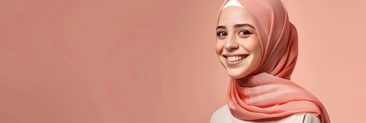 Full portrait of a young hijabi smiling woman. Peach pastel color background. Banner