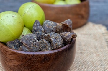Closeup of Indian Gooseberry Fruit or Amla Candy in a Wooden Bowl on Burlap Fabric Isolated on Wooden Background with Copy Space, Also Known as Emblica Myrobalan or Phyllanthus Emblica
