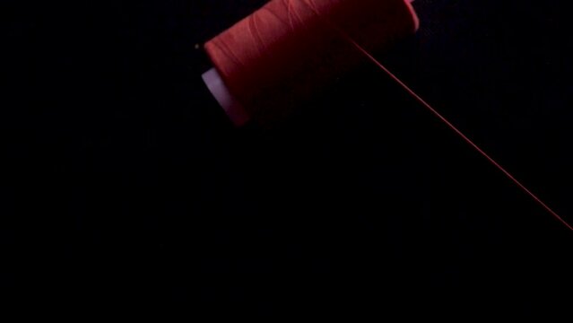 red thread spin spool on bobbin unroll fall black bg slow motion static